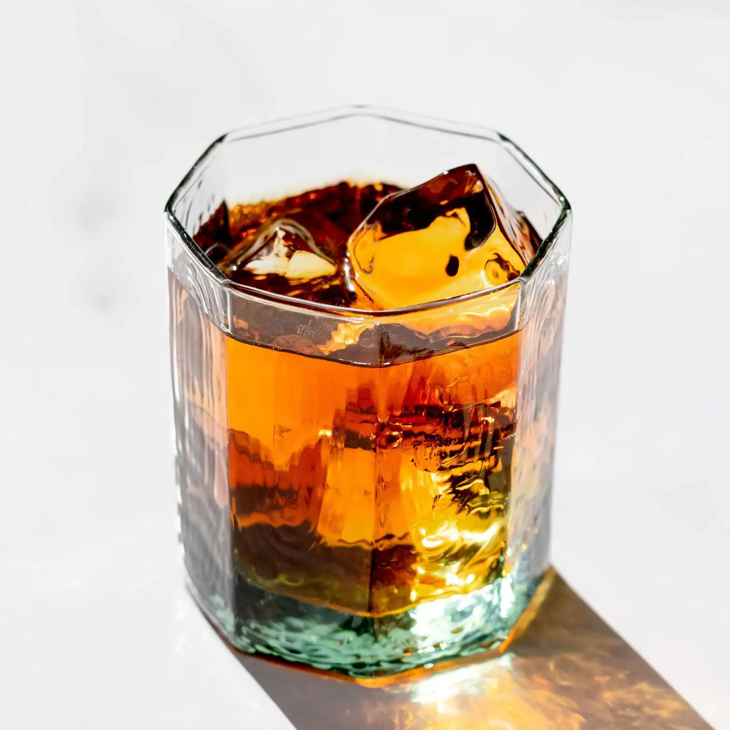 The Bottom Line single malt scotch cocktail in rocks glass with ice cubes on white surface 