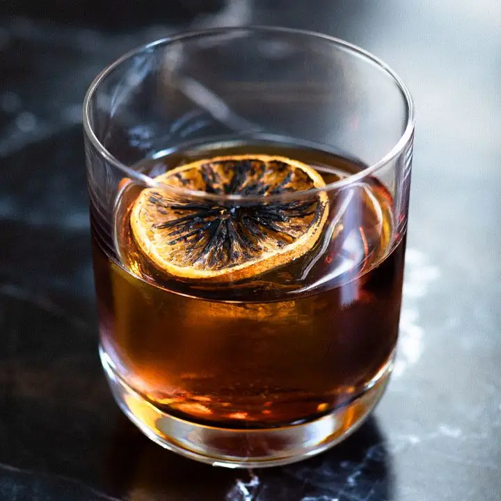 Black Negroni cocktail with flamed orange wheel