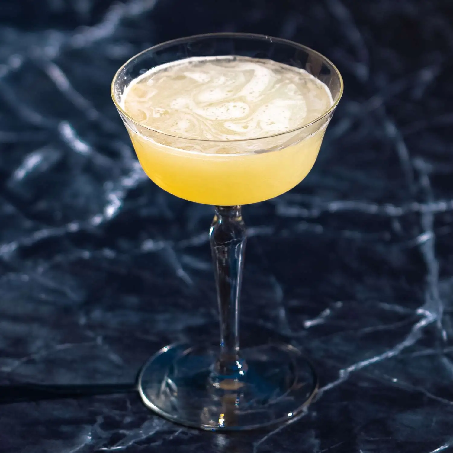 Corpse Reviver No 2 cocktail in coupe glass, shot against black marble background