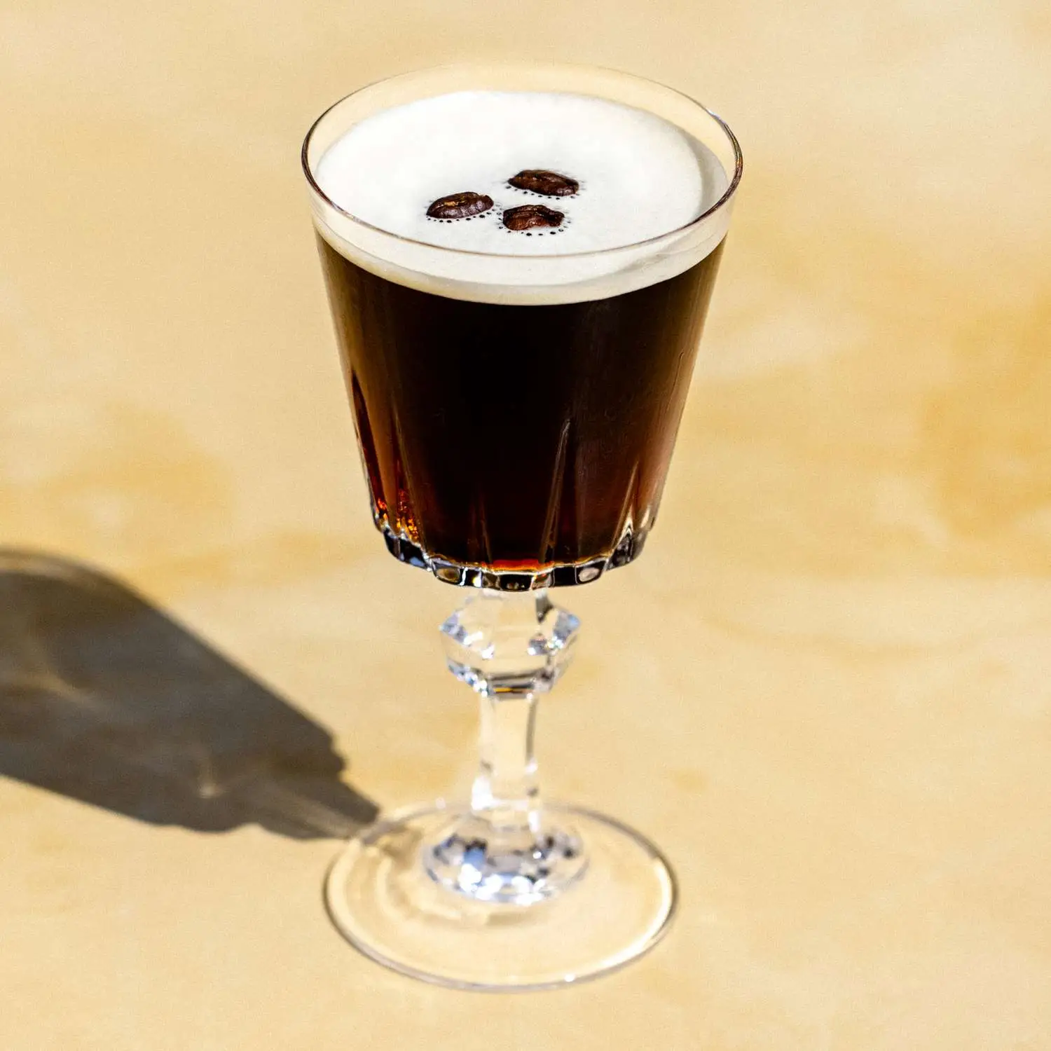 Espresso Martini in ornate footed cocktail glass, with three espresso beans as garnish