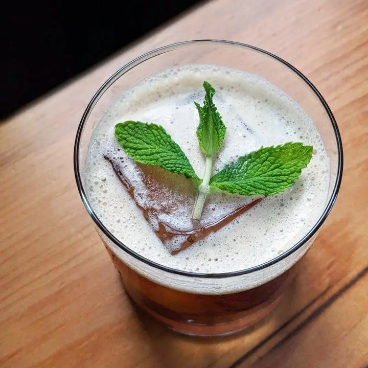 Morning After cocktail in a rocks glass, with one large ice cube and a mint sprig garnish