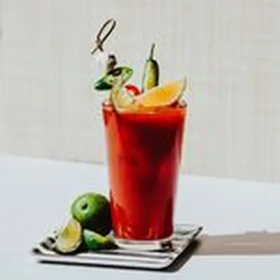 Bloody Maria on a striped coaster, garnished with citrus and peppers