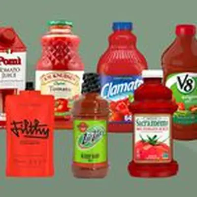 Seven different kinds of tomato juice packages against a sage green background