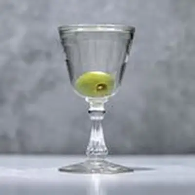 Reverse Martini in a Nick & Nora, sherry-style glass, with dropped olive garnish on marble background