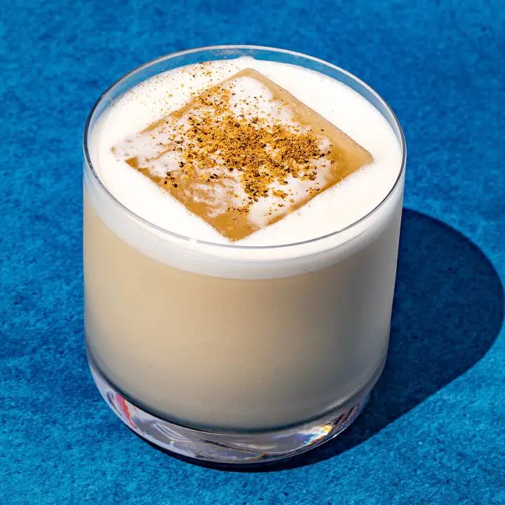 Cousin Eddie cocktail in a rocks glass with one large ice cube, garnished with black pepper, cinnamon and nutmeg