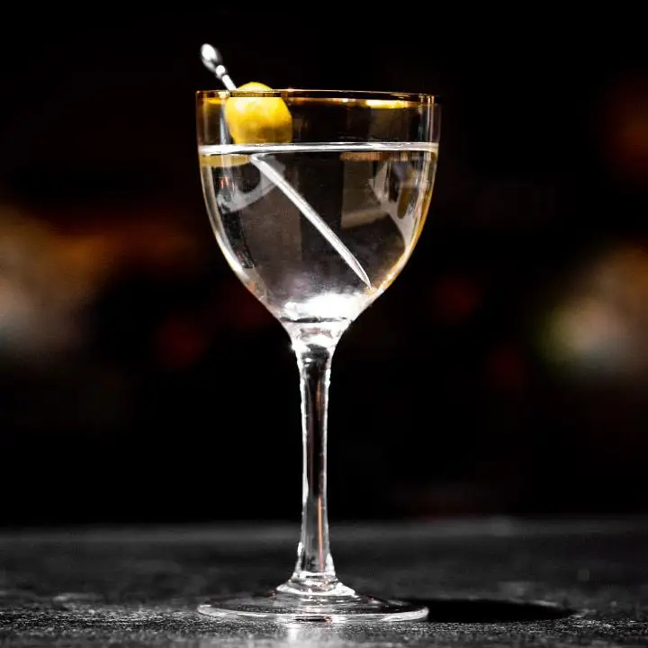 Nick & Nora Martini in a Nick & Nora glass, garnished with one olive on a metal skewer