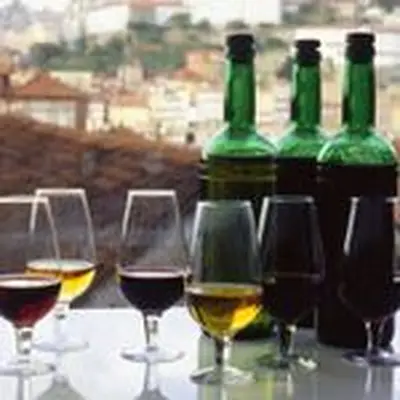 Port wine in glasses against a rooftop view of a Portuguese neighborhood and its terracotta-shingled roofs