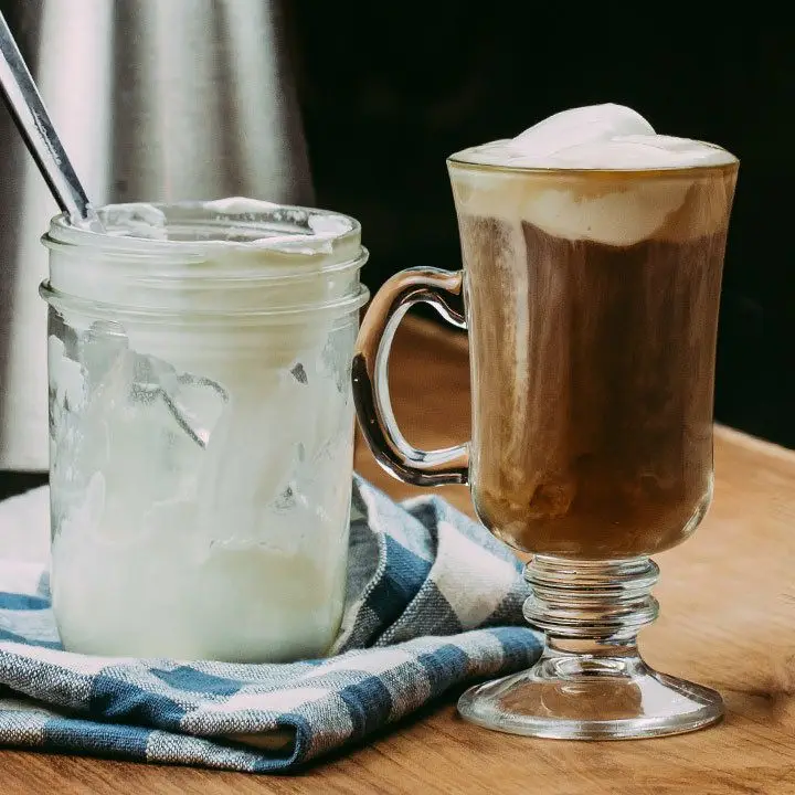 Irish Coffee Cocktail in glass mug next to a jar of cream