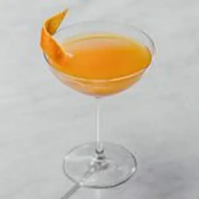orange-colored Roosevelt cocktail in a cocktail glass, garnished with an orange twist