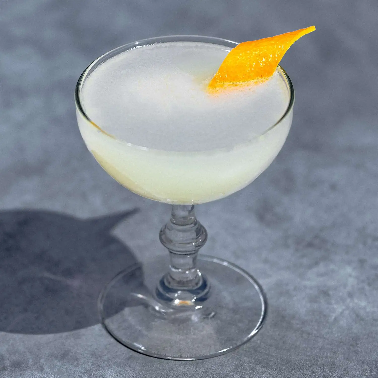 Tequila Corpse Reviver No. 2 in rounded coupe glass with orange twist, on gray marble background