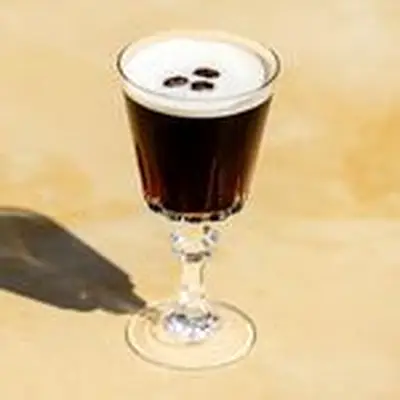 Espresso Martini in ornate footed cocktail glass, with three espresso beans as garnish