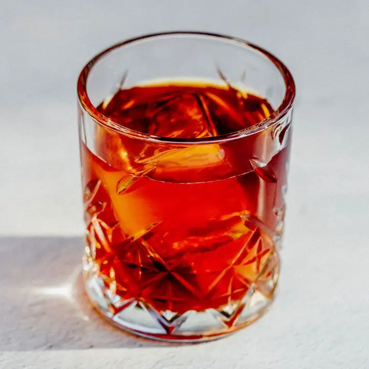red Oaxacan Tail cocktail in a crystal-cut old fashioned glass with one large ice cube
