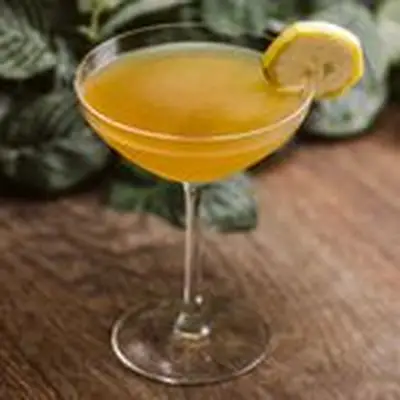 banana daiquiri cocktail on wooden table in front of green leaves