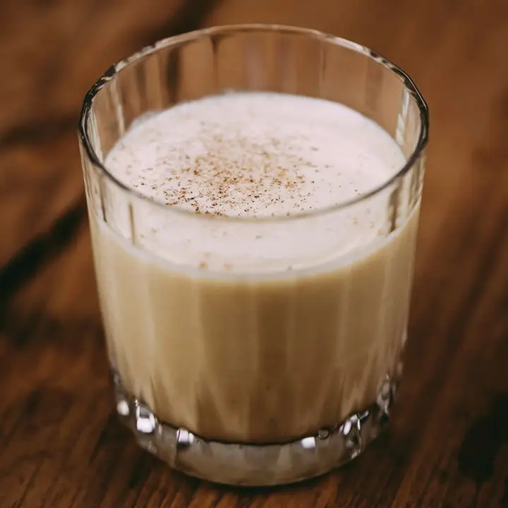 white and creamy Harvest Nog cocktail in a textured double rocks glass, with grated nutmeg on top