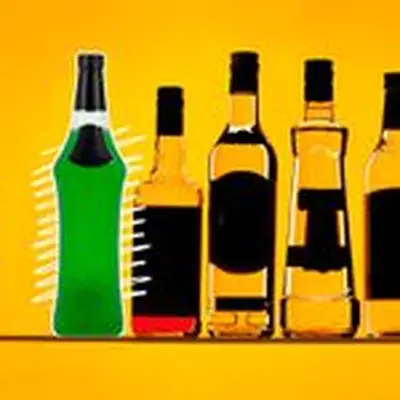 A vividly green bottle of Midori sits over zig zag white lines and a golden backdrop. Next to it are array a number of other liquor bottles, their labels darkened out