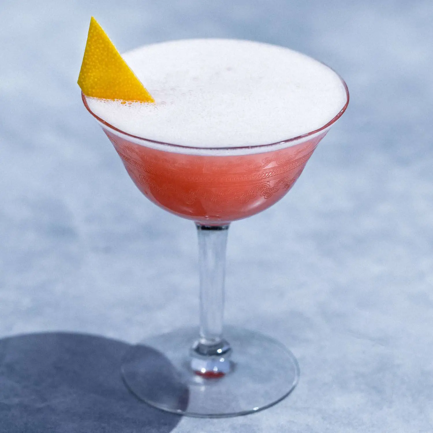Siesta cocktail served in a coupe glass and garnished with grapefruit peel, shot against marble backdrop