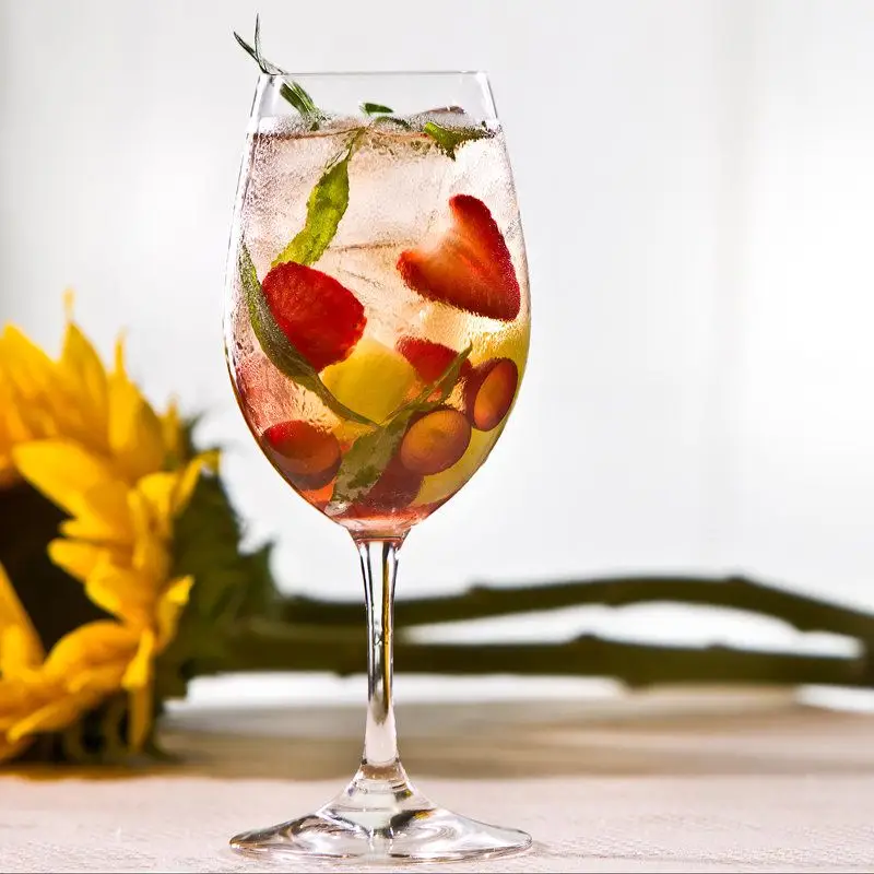 front porch swing cocktail in a wine glass with berries and herbs
