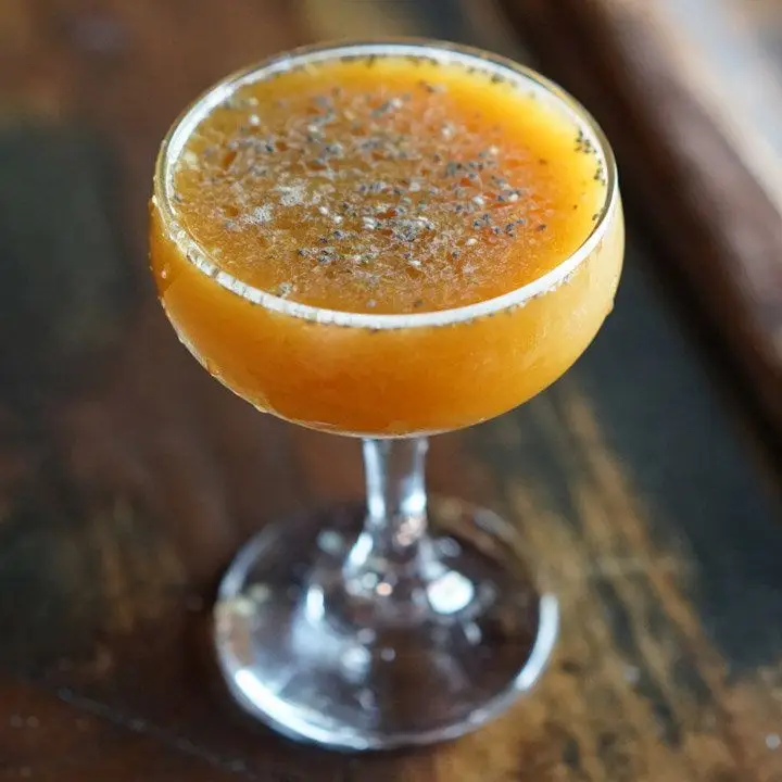 orange-colored valley of the dark lords cocktail with chia seeds on top