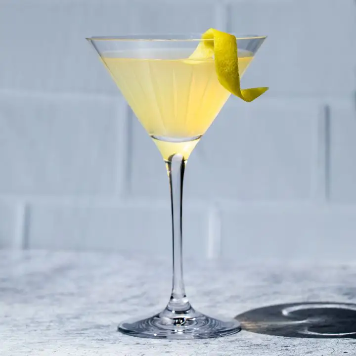 Tequila Martini with a lemon twist, set against a white tile background