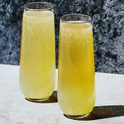 two bubbly, golden-hued Maxwell cocktails, served side-by-side in Champagne flutes