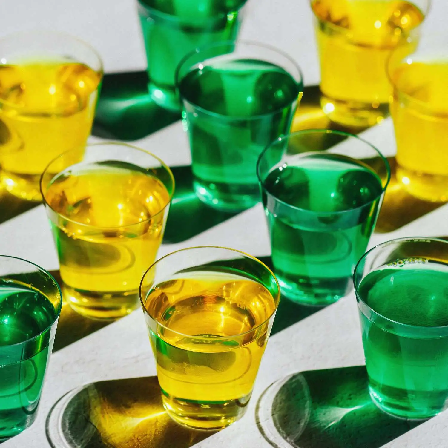 Rows of green and yellow Jell-O shots in small plastic shot cups