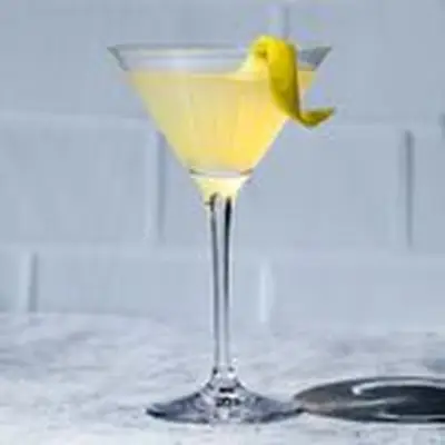 Tequila Martini with a lemon twist, set against a white tile background