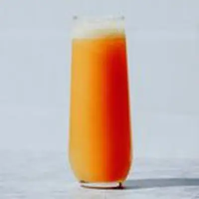 Mimosa cocktail in a stemless flute on gray background