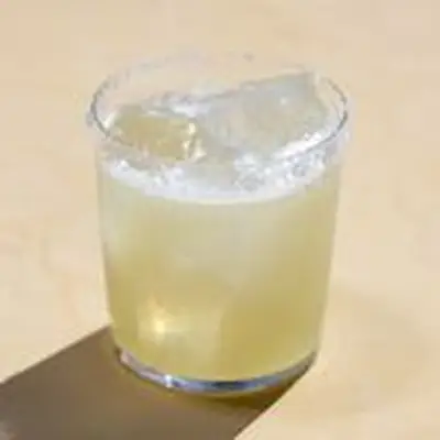 Tommys Margarita served in rocks glass with salt rim, shot against tan background