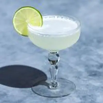 Classic Gimlet cocktail, pale green, in an old-fashioned coupe glass, garnished with a lime wheel