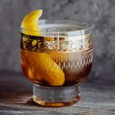 vieux carre cocktail in gold-laced glass with lemon peel garnish