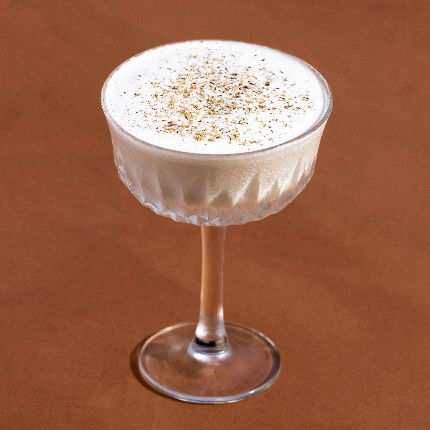 Creamy Brandy Alexander cocktail in a coupe glass with angular etching, and a dusting of nutmeg