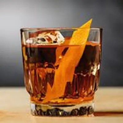 Autumn Rum Old Fashioned served in rocks glass with orange twist on wooden surface