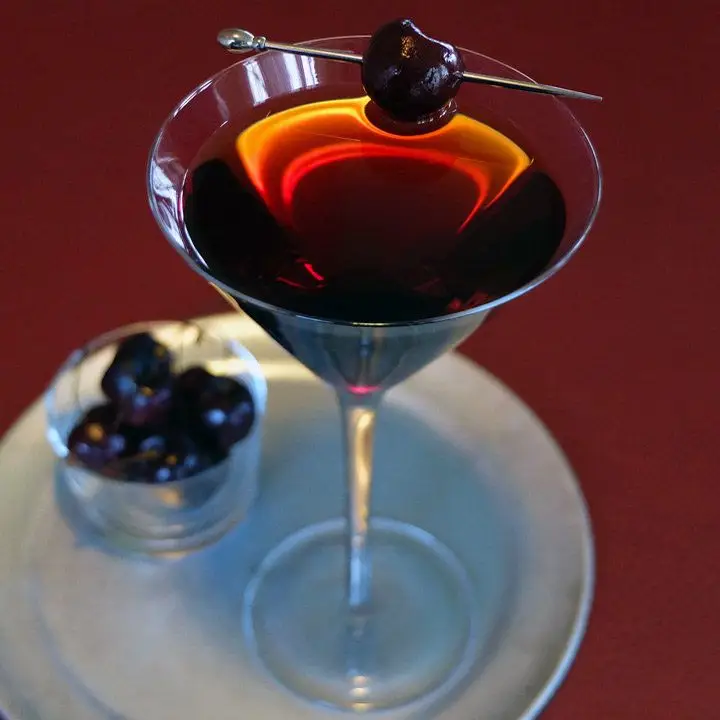 high horse cocktail with skewered cherry garnish, served on a metal tray 