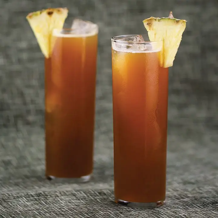 Two Surfer on Acid cocktails garnished with pineapple wedges.