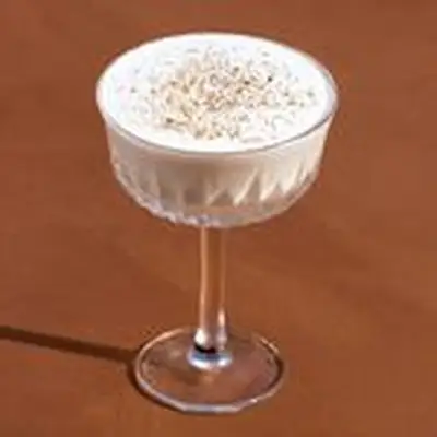 Creamy Brandy Alexander cocktail in a coupe glass with angular etching, and a dusting of nutmeg