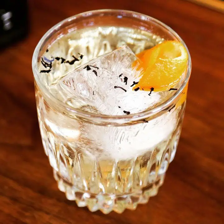 Ti’ Bijou cocktail in a rocks glass, garnished with an orange peel