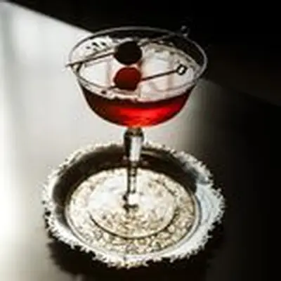 a la louisiane cocktail with cherry garnish served in a coupe glass on an ornate round metal coaster