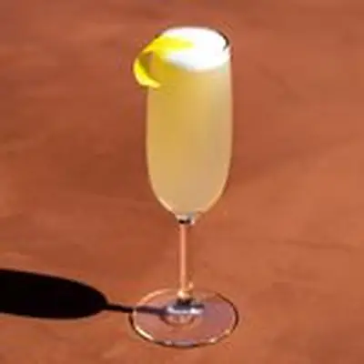 French 75 in Champagne flute with lemon twist garnish and bubbles, on dark tan background