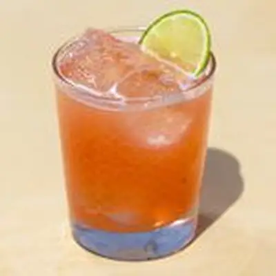 Savory Margarita cocktail served in rocks glass with cubed ice and lime wheel, shot against tan background
