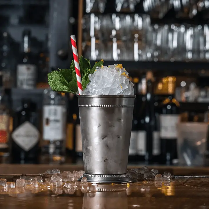Napoleon Julep cocktail in a silver julep cup, with crushed ice, mint and a red-and-white straw