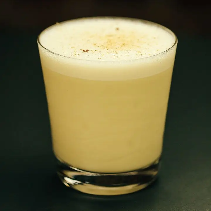 bourbon milk punch with frothy head and freshly grated nutmeg on top