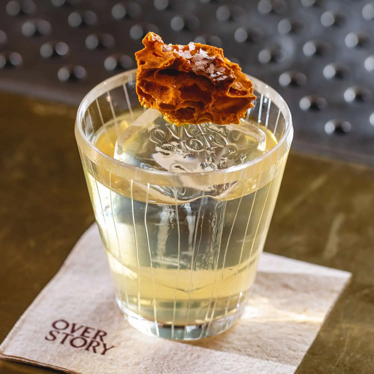 Terroir Old Fashioned in ornate rocks glass with honeycomb on top, on Overstory cocktail napkin