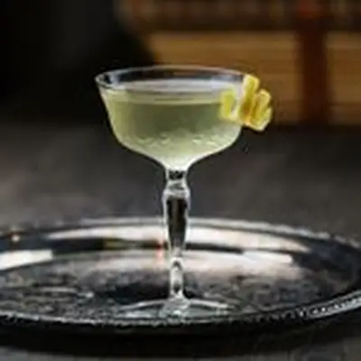 Coronation Cocktail No. 1 in a cocktail glass with a spiraled lemon twist, served on a round metal tray