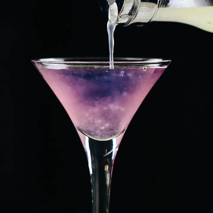 Lemon juice being poured into the Color-Changing Martini, turning it from purple to pink