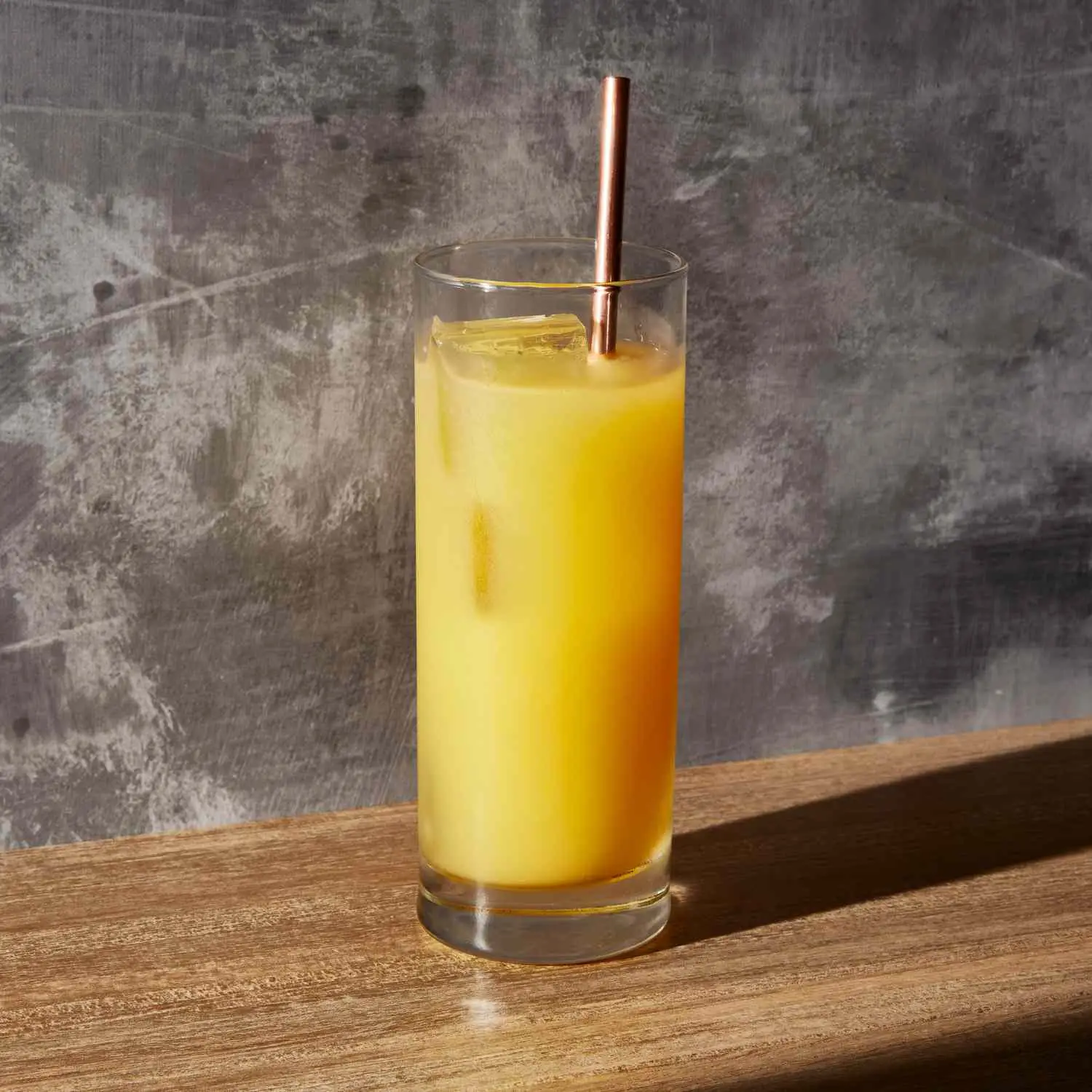 Orange Screwdriver cocktail in a highball glass with metal straw, on slate gray background