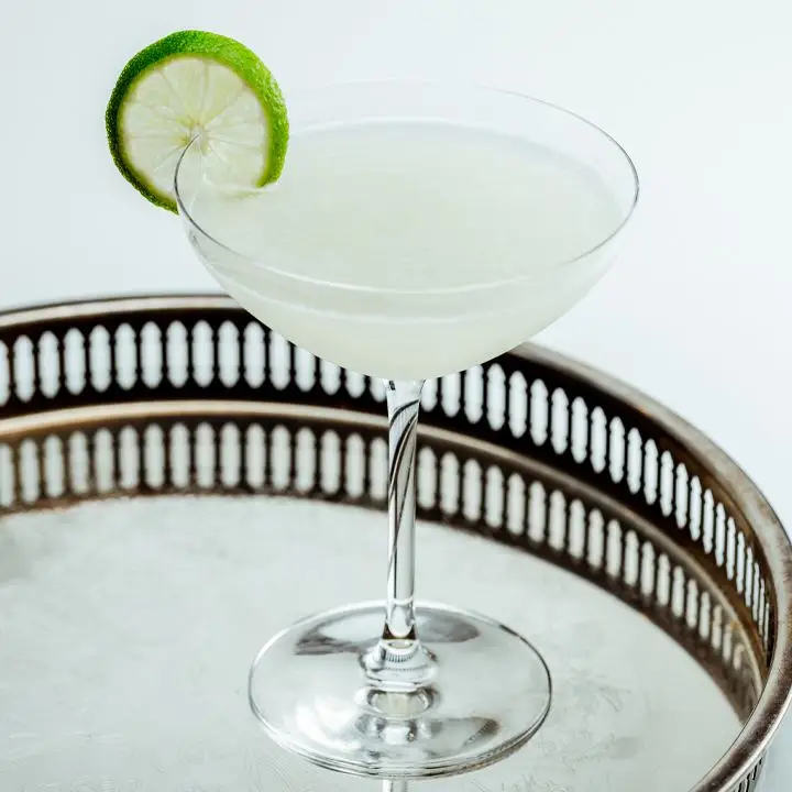 Vodka Gimlet cocktail garnished with lime wheel on circular tray