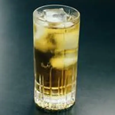 ginger ale highball cocktail with ice, served against a dark backdrop
