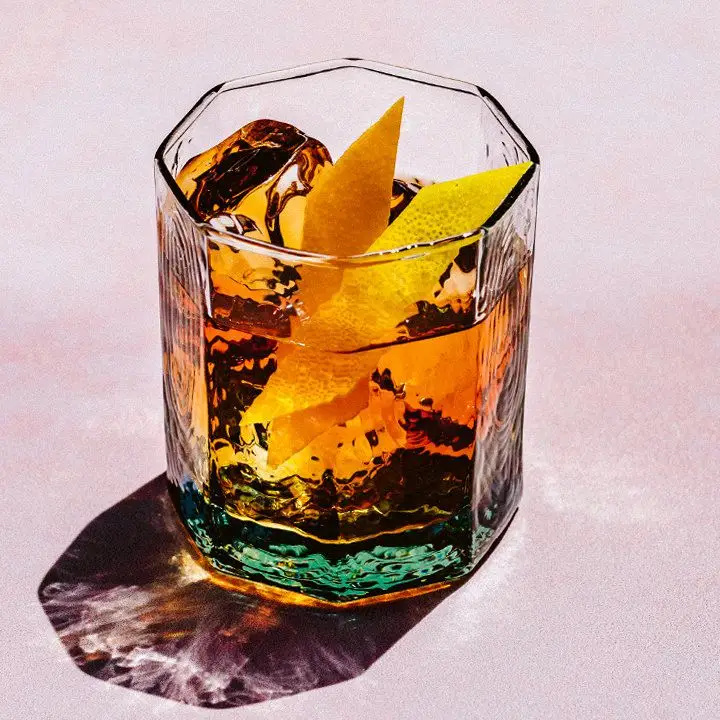 81 Old Fashioned in an octagonal rocks glass, garnished with a lemon peel and orange peel