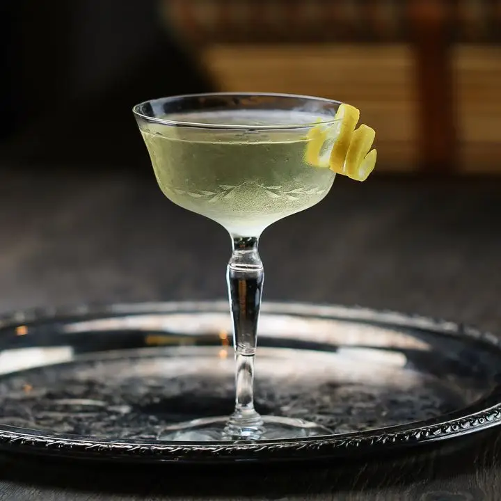 Coronation Cocktail No. 1 in a cocktail glass with a spiraled lemon twist, served on a round metal tray