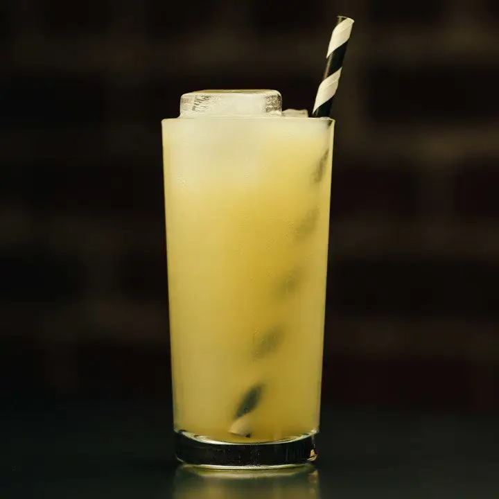 Momisette cocktail in a Collins glass with ice and a black-and-white straw